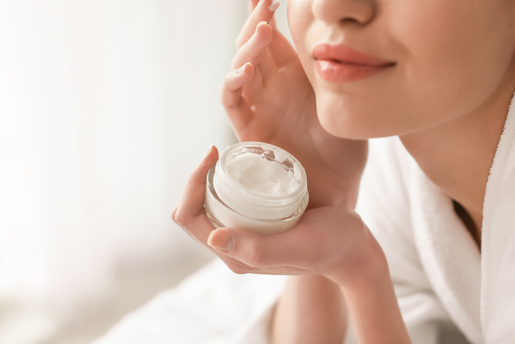 Woman Applying Cream onto Her Skin